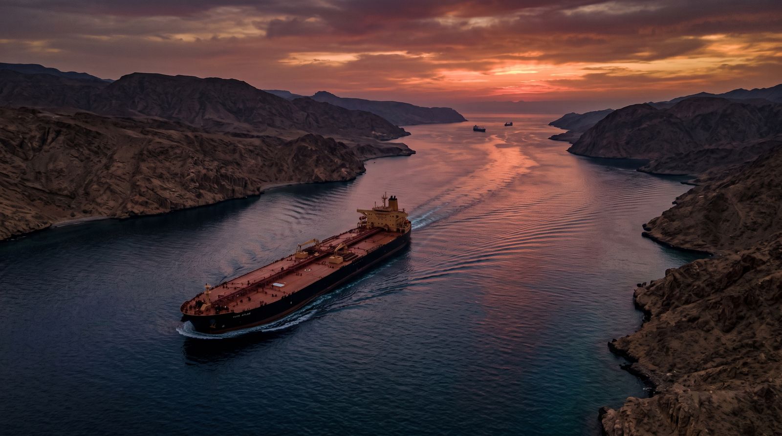 Oil tanker transiting a narrow strait at dusk