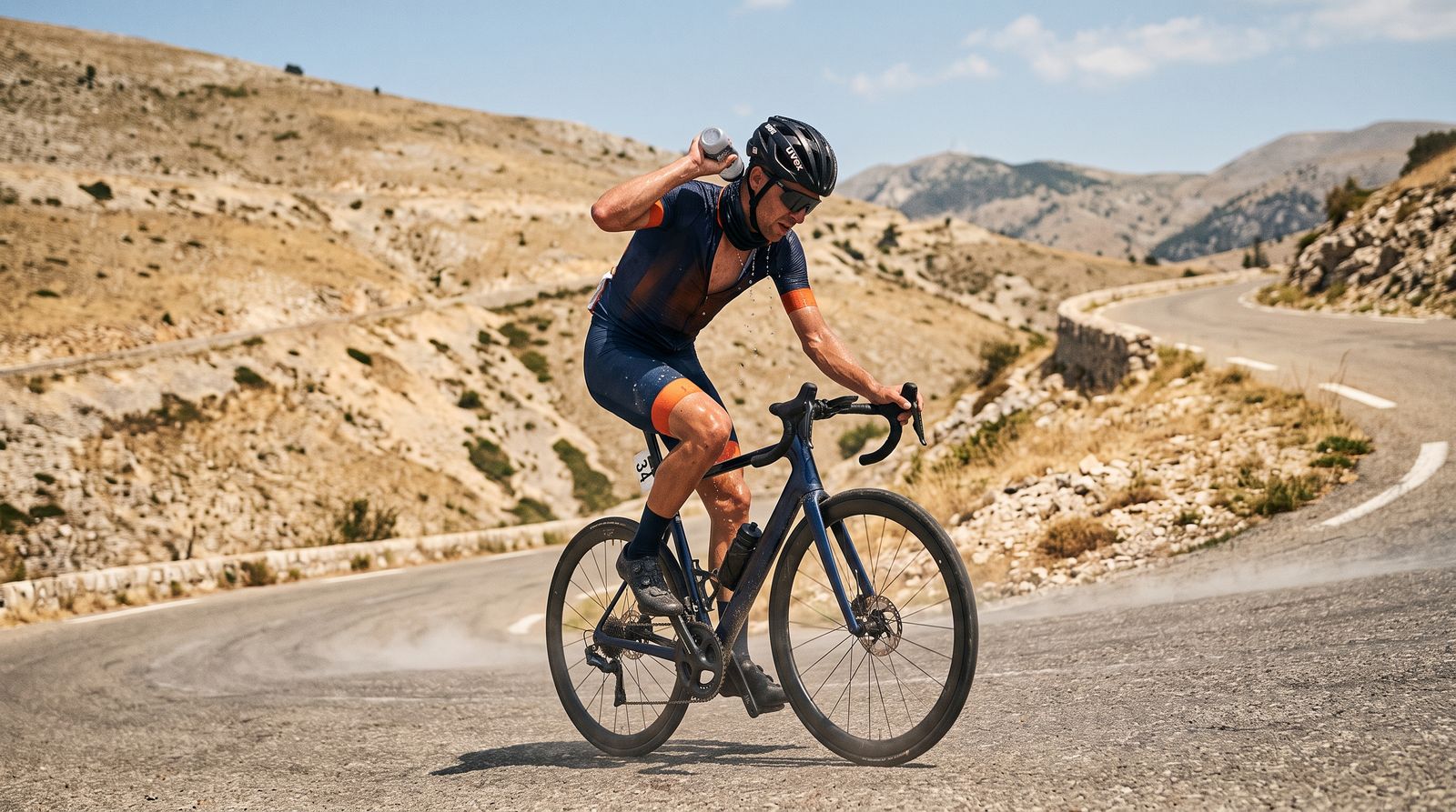 A lone cyclist pours water over their neck while climbing a sun-baked mountain road in extreme heat